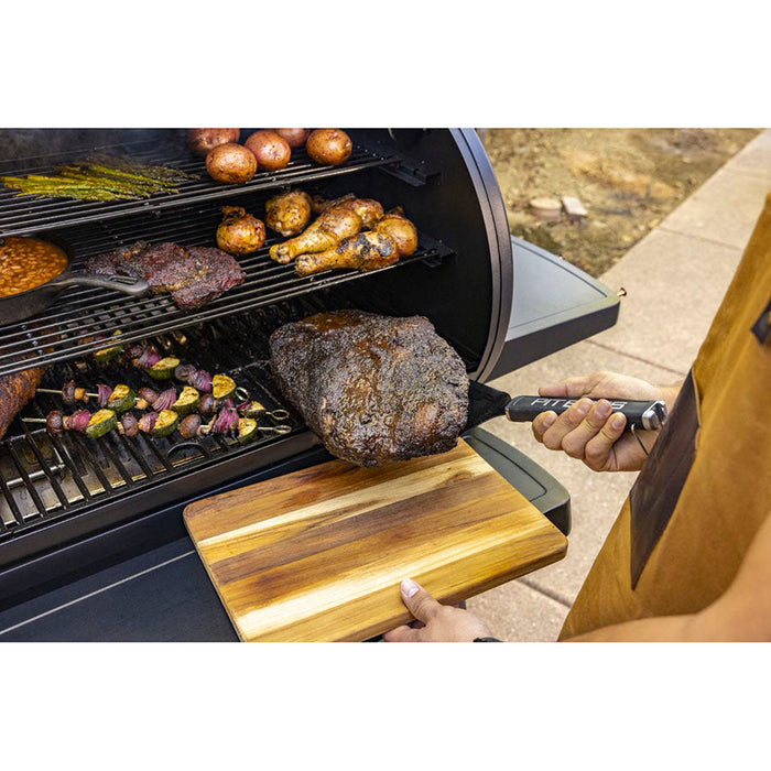 Close up of the big head spatula being used to take meat out of the grill outside.