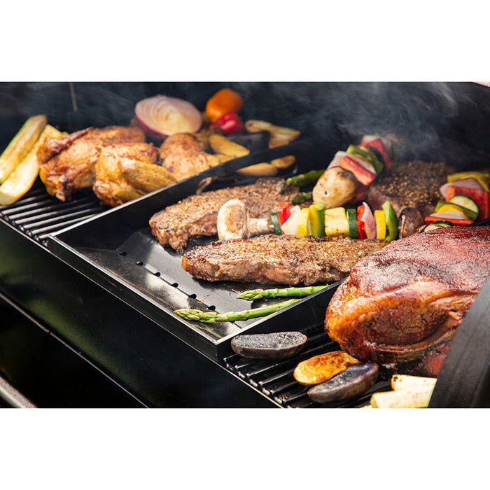 Meats cooking on griddle insert and cooking gates. Close up. Smoke. Grill hood open. Side view.