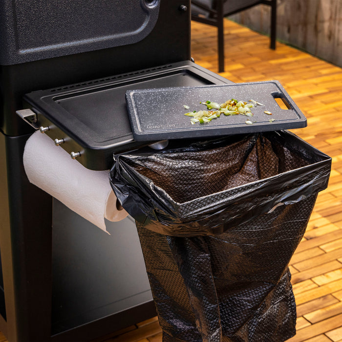 Black Pit Boss Grills Deluxe Folding Side Shelf with attached cutting board and trash bag holder.