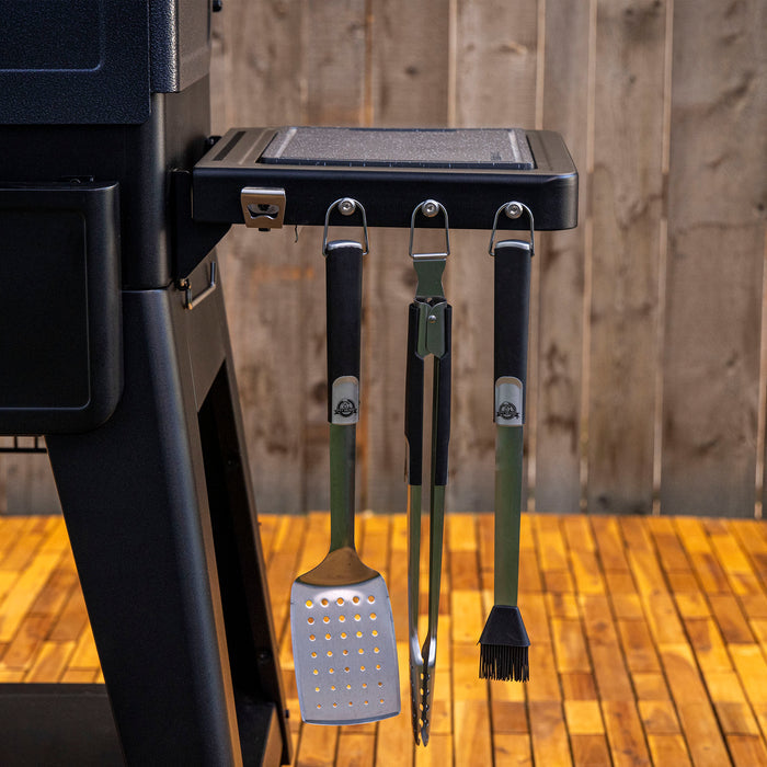 Pit Boss Grills Deluxe Folding Side Shelf in black, designed for grilling upgrades, with hanging tools.