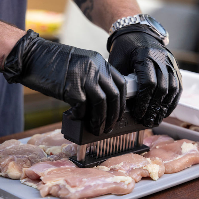 Pit Boss Food Prep Kit meat tenderizer tenderizing chicken on cutting board before going into grill