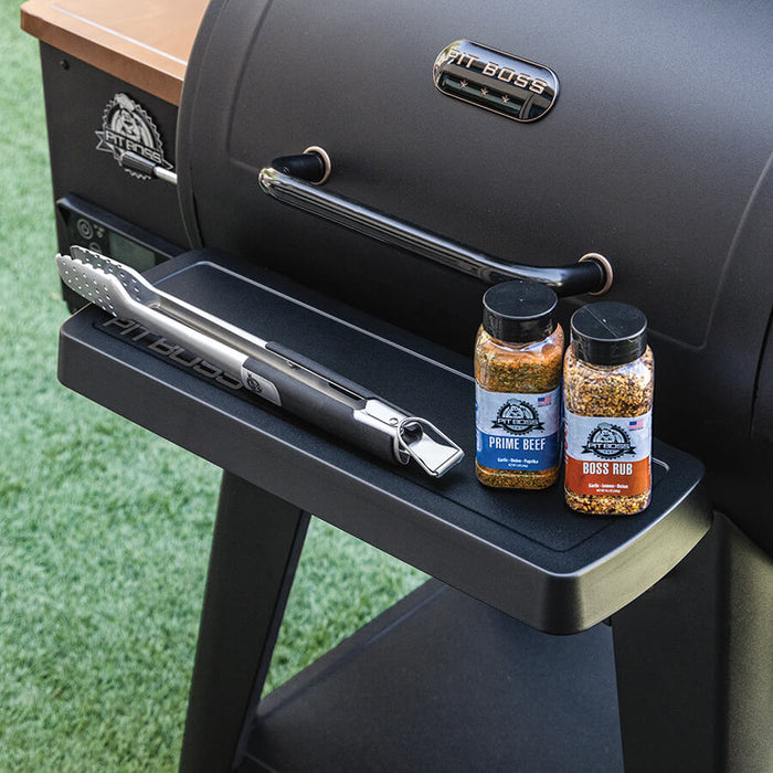 Black Pit Boss Grills 700 Series Onyx/DX front shelf with tongs and seasoning bottles.