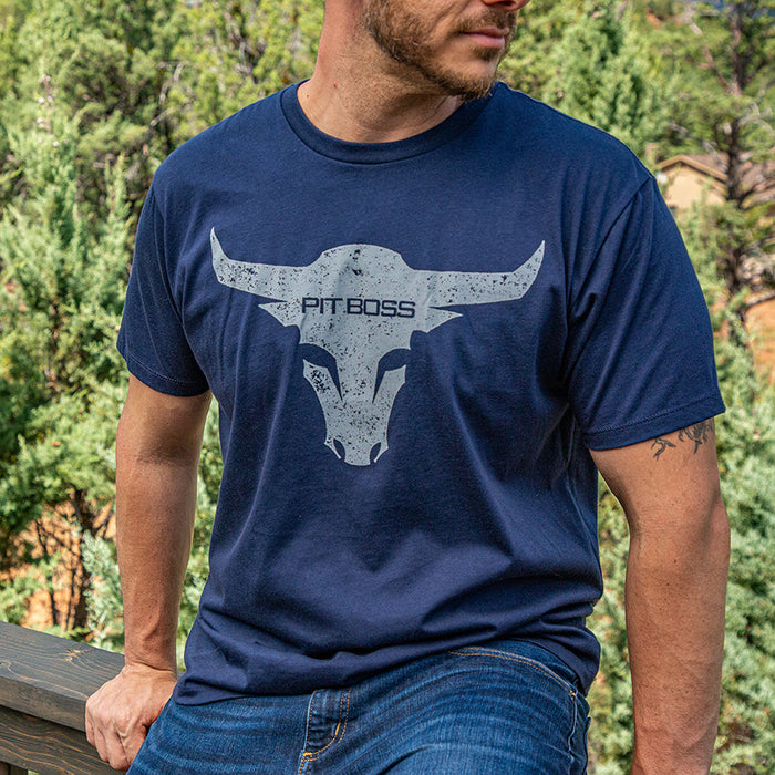 Midnight navy Pit Boss Grills t-shirt with white bull graphic and "PIT BOSS" text, worn by a man outdoors.