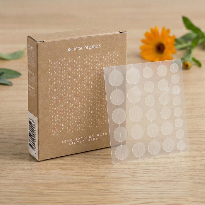 Norse Organics Acne Patches box and patch sheet on wood beside a calendula flower