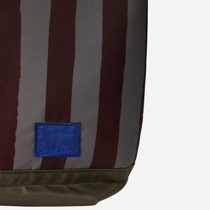 The Paul Smith signature on a blue patch on the front of the Paul Smith Multistripe Recycled Nylon Adjustable Tote Bag with Signature Logo Patch.
