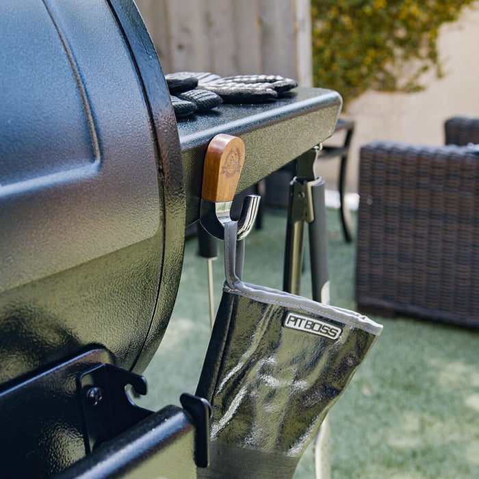 Magnetic hook hanging on Pit Boss grill with Pit Boss glove hanging off of it.