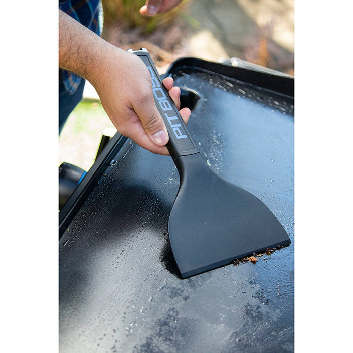 Diddle scraper collecting crumbs on griddle and cleaning.